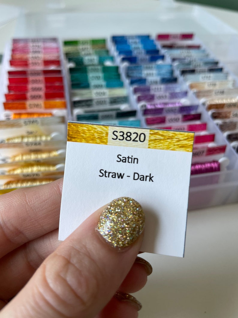 May include: A close-up of a spool of embroidery floss labeled "S3820 Satin Straw - Dark".