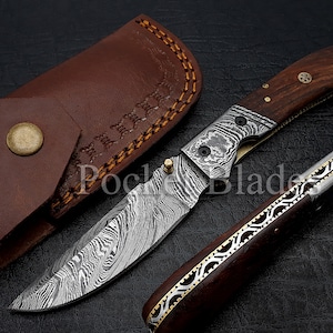 May include: A folding pocket knife with a wood handle and a damascus steel blade. The knife is open and the blade is sharp. The knife comes with a brown leather sheath.