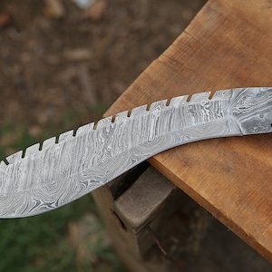 May include: A curved, silver-colored knife with a serrated edge and a patterned blade. The handle is made of wood and bone with a brass accent.
