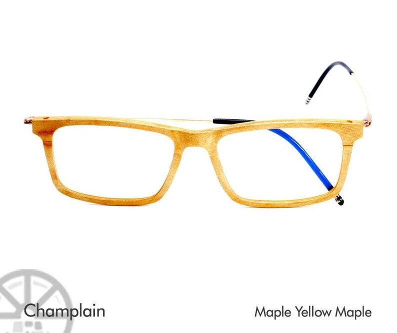 K&ouml;nnte beinhalten: Holzbrille mit einem Ahornholzrahmen und blauen B&uuml;geln. Der Rahmen ist hellbraun und die B&uuml;gel sind dunkelblau. Die Brille hei&szlig;t "Champlain" und ist aus "Maple Yellow Maple" gefertigt.