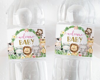 Może przedstawiać: Dwie przezroczyste plastikowe butelki z wodą z etykietami, na których napisano "welcome baby" różowymi i złotymi literami. Etykiety przedstawiają motyw dżungli z lwem, zebrą, słoniem, żyrafą i małpą.
