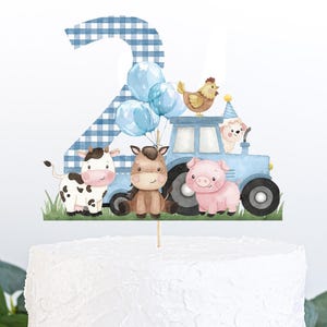 May include: Blue and white checkered number two cake topper with a blue tractor, a cow, a horse, a pig, and a chicken. The topper is on a white cake.