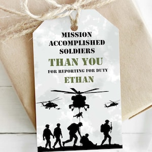 May include: A white tag with green text that reads "Mission Accomplished Soldiers Than You For Reporting For Duty Ethan". The tag features a silhouette of a helicopter and soldiers.