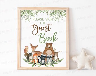 May include: A sign with a woodland theme that says "Please sign the Guest Book". The sign features a brown bear, a deer, an owl, a fox, a raccoon, and a squirrel surrounded by green leaves.