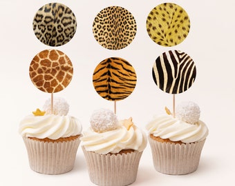 May include: Cupcakes with white frosting and animal print toppers. The toppers feature patterns of leopard, cheetah, giraffe, tiger, and zebra. Each cupcake is decorated with a white candy ball and a gold star.