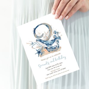 Op de afbeelding: Een blauwe en gouden aquarel-uitnodiging voor een tweede verjaardag. De uitnodiging toont een walvis die door een koraalrif zwemt, met het nummer twee op de achtergrond. De tekst op de uitnodiging luidt: "Kom gezellig meevieren met ons de 2e verjaardag van Samuel. Zondag 30 november 20XX. Van 15:00 tot 18:00 uur. Bij Samuel. 4234 Sweet Drive, Love CA 18765. Laat het ons weten voor 15 november via [naam] op 000-000-0000."
