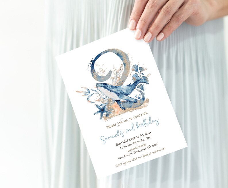 Op de afbeelding: Een blauwe en gouden aquarel-uitnodiging voor een tweede verjaardag. De uitnodiging toont een walvis die door een koraalrif zwemt, met het nummer twee op de achtergrond. De tekst op de uitnodiging luidt: "Kom gezellig meevieren met ons de 2e verjaardag van Samuel. Zondag 30 november 20XX. Van 15:00 tot 18:00 uur. Bij Samuel. 4234 Sweet Drive, Love CA 18765. Laat het ons weten voor 15 november via [naam] op 000-000-0000."