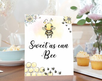 May include: A white sign with a cute cartoon bee illustration and the text "Sweet as can Bee". The sign is decorated with yellow honeycomb and small bees.