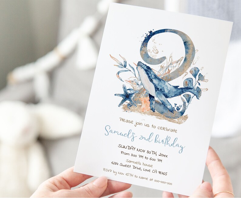 Op de afbeelding: Een blauwe en gouden uitnodigingskaart met een aquarel-illustratie van een walvis die door zeewier zwemt en een groot nummer 2. De tekst op de kaart luidt "We nodigen u uit om de 2e verjaardag van Samuels te vieren, zondag 30 november 20xx, van 15:00 tot 18:00 uur, bij Samuels, 1234 Sweet Drive, Love CA 98765, RSVP v&oacute;&oacute;r 15 november aan Name op 000-000-000".