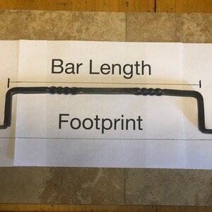 May include: A black metal bar with a twisted design, measuring the bar length and footprint. The bar is approximately 12 inches long.