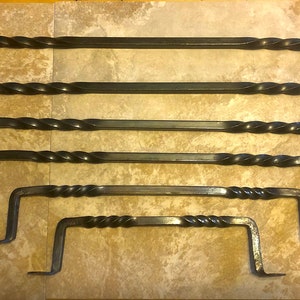 May include: Set of six black wrought iron towel bars with a twisted design. The bars are of varying lengths and are arranged in order of size.