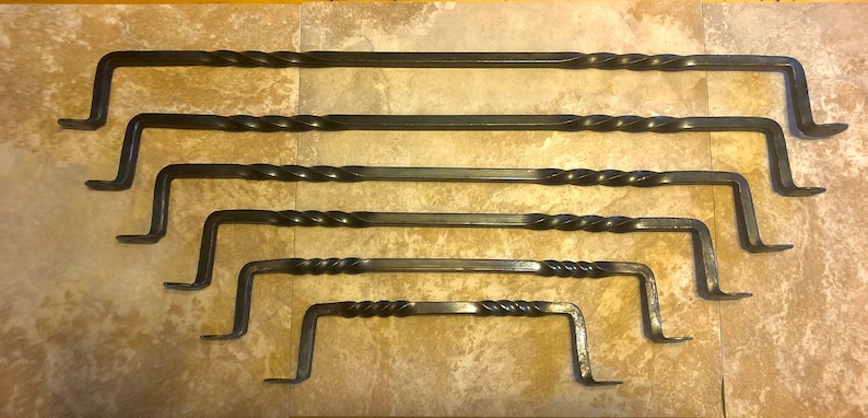 May include: Set of six black wrought iron towel bars with a twisted design. The bars are of varying lengths and are arranged in order of size.