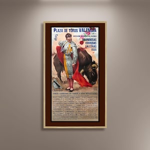 May include: Framed vintage poster for Plaza de Toros Valencia, featuring a matador with a red cape facing a black bull. The poster includes text in Spanish, advertising bullfights in 1986. The frame is a light beige colour.