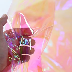 Puede incluir: Una lámina de vinilo holográfico iridiscente con un brillo arcoíris. La lámina es translúcida y tiene un acabado liso y brillante.