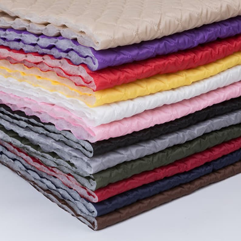 May include: A stack of 14 different colored quilted fabrics. The fabrics are arranged in a rainbow pattern, with the lightest color at the top and the darkest color at the bottom.