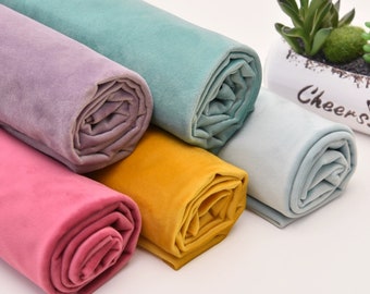May include: Five rolls of fabric in different colors: light blue, purple, yellow, pink, and light gray. The fabric is soft and velvety.