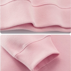 Op de afbeelding: Close-up van de roze geribbelde manchet van een sweatshirt. De stof is zacht en comfortabel.
