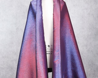 May include: A piece of iridescent fabric with a gradient of red to purple. The fabric is draped over a white dress form. The fabric has a subtle shimmer and a smooth texture.