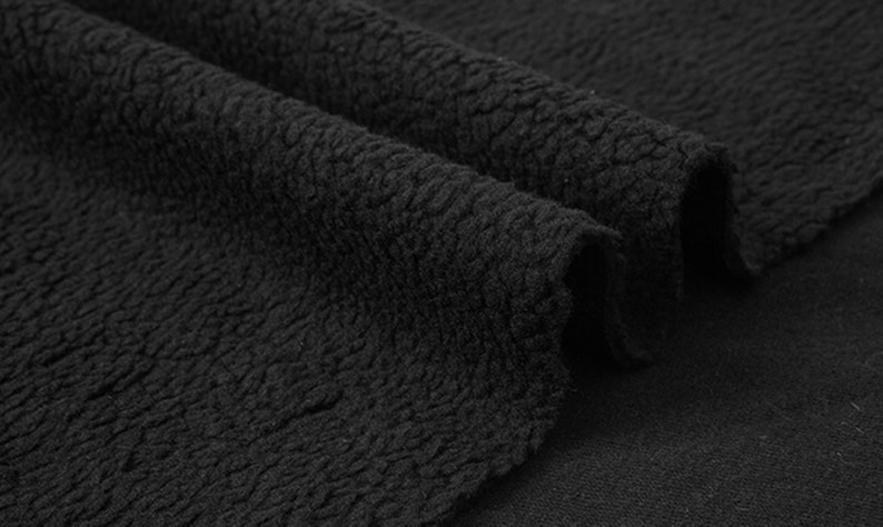 May include: Close-up of black fleece fabric with a textured surface.