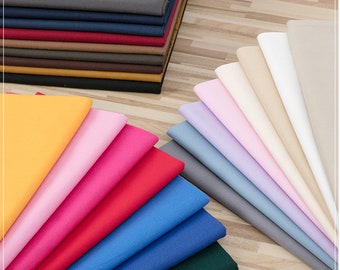 May include: A stack of fabric swatches in various colours, including yellow, pink, red, blue, green, grey, beige, and white. The fabric is arranged in a fan shape, with the lightest colours at the top and the darkest colours at the bottom.