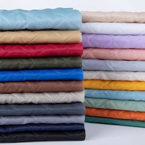 May include: A stack of 20 different colored quilted fabrics. The fabrics are all in a diamond pattern and are arranged in a staggered pattern.