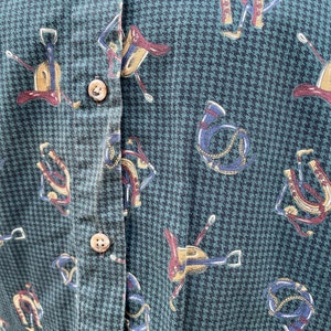 Pu&ograve; includere: Una camicia verde e nera con bottoni, con un motivo pied-de-poule e un motivo ripetuto di immagini equestri, tra cui selle, staffe e briglie.