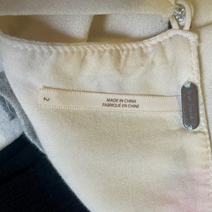 May include: A white garment with a label that reads "Made in China Fabrique en Chine" and a size tag that says "2". The garment also has a small metal tag that says "Free People".