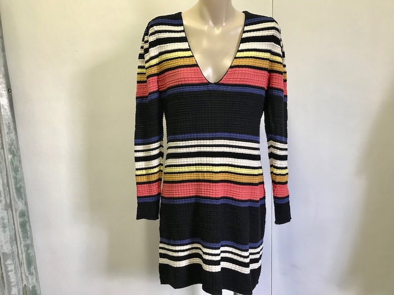 Puede incluir: Un vestido de manga larga a rayas blancas y negras con rayas de colores en rosa, amarillo y azul.