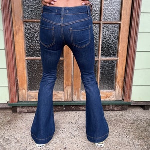 May include: A pair of dark blue denim bell bottom jeans with a high waist and a slim fit through the thigh.