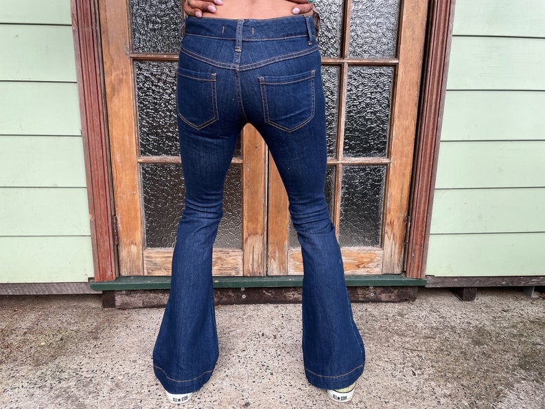 May include: A pair of dark blue denim bell bottom jeans with a high waist and a slim fit through the thigh.