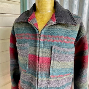 Puede incluir: Una chaqueta a rayas de varios colores con cierre de cremallera y cuello de pana. La chaqueta está hecha de un material suave y peludo y tiene dos bolsillos en la parte delantera.