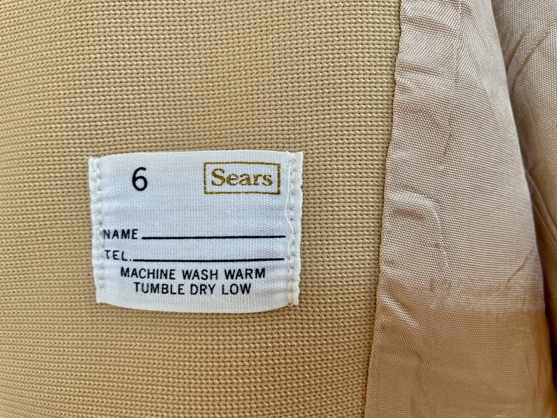 May include: White label with the text "Sears" and the number "6" printed on it. The label also includes the text "Name", "Tel", "Machine Wash Warm", and "Tumble Dry Low".