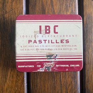 May include: A red and white tin box with the text "IBC IODIZED BLACKCURRANT PASTILLES" and "MANUFACTURED FOR Rubs NOTTINGHAM, ENGLAND."