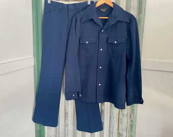 Puede incluir: Un traje azul marino con camisa de manga larga y pantalón a juego. La camisa tiene cuello de punta y cierre de botones.