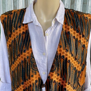May include: A brown and black patterned waistcoat with beaded embellishments. The waistcoat has a V-neck and is made of a silky fabric.