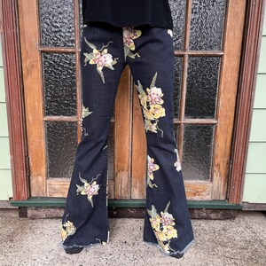 May include: Black flared jeans with a floral print of yellow and pink orchids.