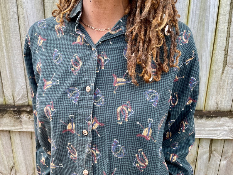 Pu&ograve; includere: Una camicia a maniche lunghe abbottonata a quadri verdi e bianchi con una stampa di cavallo e ferro di cavallo.