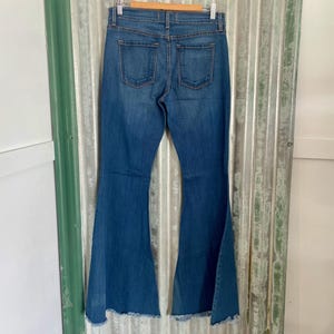 May include: A pair of blue denim bell bottom jeans with a frayed hem.