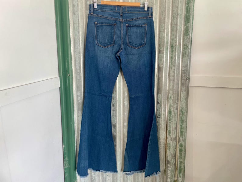 May include: A pair of blue denim bell bottom jeans with a frayed hem.