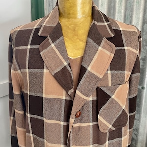 May include: A brown and beige plaid jacket with a single button closure. The jacket has a patch pocket on the left side.