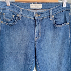 May include: A pair of dark blue denim jeans with a small pocket on the front left leg and a label that reads "FP" on the back waistband.