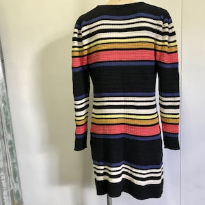 Puede incluir: Un vestido de manga larga a rayas blancas y negras con rayas horizontales de colores en amarillo, naranja, rosa y azul.