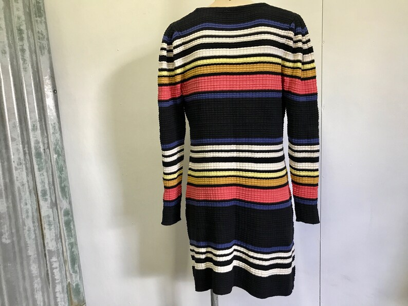 Puede incluir: Un vestido de manga larga a rayas blancas y negras con rayas horizontales de colores en amarillo, naranja, rosa y azul.
