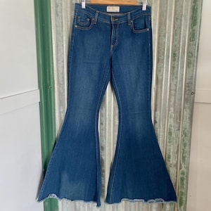 May include: A pair of blue denim bell bottom jeans with a frayed hem.