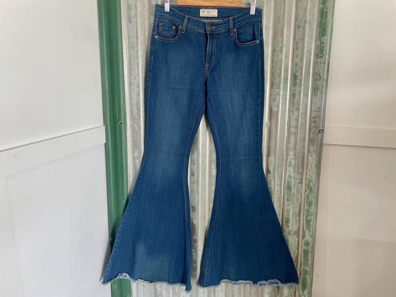 May include: A pair of blue denim bell bottom jeans with a frayed hem.