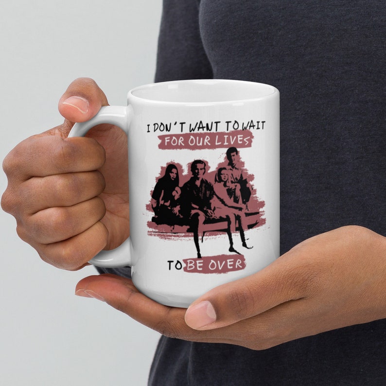 May include: White ceramic mug with a pink graphic of four people sitting on a bench. The text on the mug reads "I don't want to wait for our lives to be over."