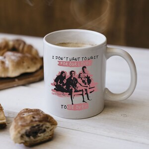 May include: White ceramic mug with a black and white image of a band with the text "I don't want to wait for our lives to be over" in pink.