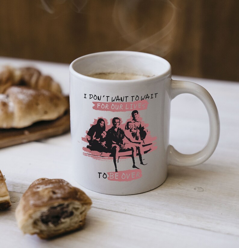 May include: White ceramic mug with a black and white image of a band with the text "I don't want to wait for our lives to be over" in pink.