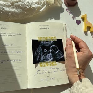 Premium linen pregnancy journal keepsake in soft beige with embossed gold title on a white background GROWING YOU. Ultrasound pages inside pregnancy journal.