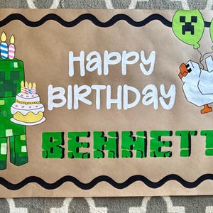 May include: A rectangular brown paper banner with a black wavy border featuring a green pixelated character holding a birthday cake with candles, a white chicken with green balloons, and the text Happy Birthday BENNETT in white and green.